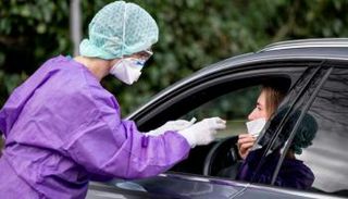 طبيبة تجري فحص كورونا لسيدة بموقف للسيارات في مدينة ألمانية