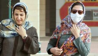 سيدة تضع الكمامة أثناء سيرها في الشارع خشية كورونا