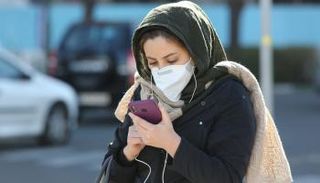 سيدة تضع كمامة أثناء سيرها في الشارع للوقاية من كورونا