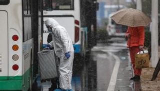 أحد عمال الرعاية الصحية يساعد مريضا في ووهان - واشنطن بوست