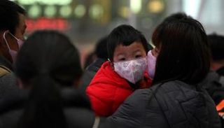 سيدة تحمل طفلها ويضعان الكمامة للوقاية من كورونا