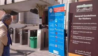 سائح أمام لافتة توعية بمخاطر "كورونا" داخل المتحف المصري