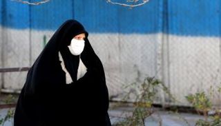 سيدة تضع كمامة أثناء سيرها في الشارع للوقاية من كورونا