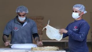 عاملان يرتديان كمامة خشية كورونا في قطاع غزة