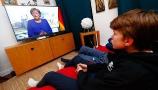 ألمان يتابعون كلمة لميركل عبر شاشات التلفزيون