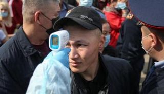 فحص درجة الحرارة لرجل ينتظر في طابور لدخول العاصمة