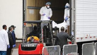 عمال الرعاية الصحية يستخدمون رافعات لتحميل الجثث