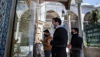 أشخاص يرتدون كمامات أمام مسجد بإسطنبول