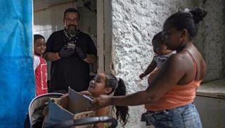 فتاة صغيرة تحمل علبة مليئة بالمواد الغذائية ومواد التنظيف 