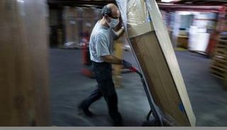  عامل بأكبر مصنع للنعوش في أوروبا ينقل تابوتا لتخزينه