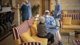 عامل إغاثة إسباني يتحدث إلى مسنة قبل اختبار كورونا