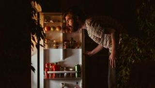 شاب يقف أمام ثلاجة