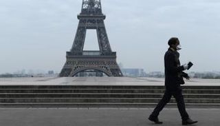 فرنسي يمر بجانب برج إيفل
