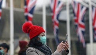 سيدة ترتدي الكمامة وتلتقط صورة في أحد شوارع لندن