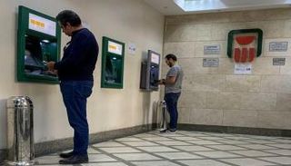 عملاء أمام ماكينات صرافة تابعة للبنك الأهلي المصري - رويترز
