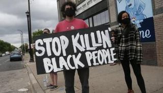 محتج يرفع لافتة بعد مقتل رجل من أصل أفريقي 