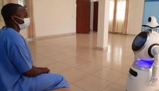 روبوت يقيس درجة حرارة أحد أفراد الطاقم الطبي في كيجالي- رويترز
