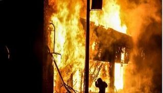 متظاهر بجانب مبنى مشتعل جراء الشفب بمدنية مينيابوليس - الفرنسية