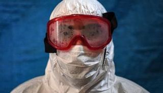 أحد أعضاء الفرق الطبية  يرتدي الملابس الواقية من العدوى