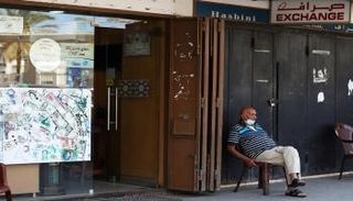 رجل يجلس خارج متجر للصرافة في بيروت - رويترز