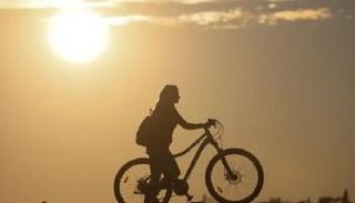 فتاة تسير بجوار عجلة تحت أشعة الشمس - الجارديان