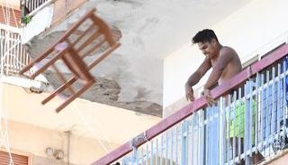 أحد سكان المجمع السكني يلقي كرسيا على المتظاهرين أسفل المبنى