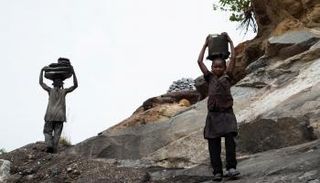 طفلان يحملان ماء فوق رأسيهما 