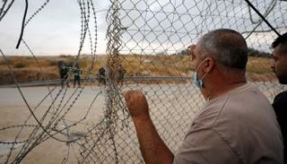 فلسطيني يقف أمام أحد المعابر الإسرائيلية