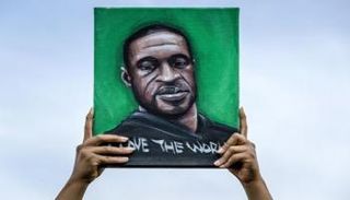 متظاهر أمريكي يحمل صورة جورج فلويد - أ.ف.ب