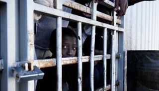 طفل مهاجر ينظر من نافذة أحد مراكز الإيواء