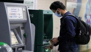 عميل أمام ماكينة صرافة تابعة للبنك الأهلي المصري - رويترز