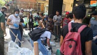 شباب يزيلون الزجاج المتناثر في شوارع بيروت