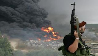 أحد مسلحي حزب الله ينظر إلى حريق بإحدى ضواحي بيروت 