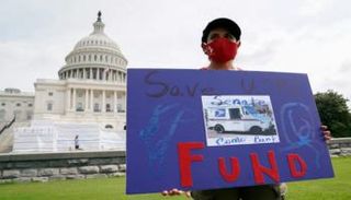 سيدة تحمل لافتة تطالب بدعم البريد أمام الكونجرس الأمريكي 