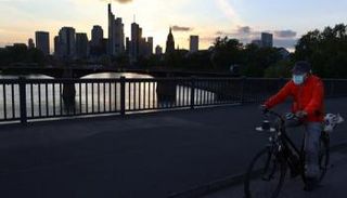 راكب دراجة يمر أمام الحي المالي بفرانكفورت عند غروب الشمس