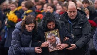 والدة الطيار الأوكراني تحمل صورته وزوجته إلى يمينها - أرشيفية