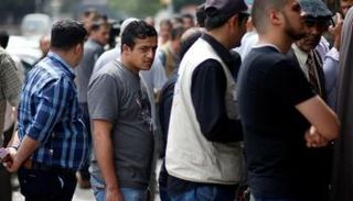 موظفون حكوميون في السلطة الفلسطينية يقفون في طابور لاستلام رواتبهم