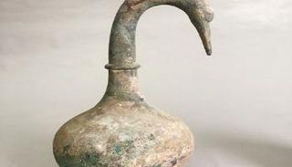 وعاء برونزي مصنوع على شكل بجعة بداخله سائل بني غامض