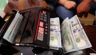 موظف بأحد مصارف ليبيا يحصي أوراقًا من فئة الـ100 دولار. (أرشيفية)ليبيا