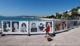 سيدة تسير بجوار مجموعة صور تخص دورة سابقة لمهرجان كان