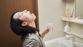 سيدة تتغرغر بالماء والملح لقتل الفيروسات الموجودة في الحلق