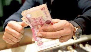 موظف بأحد مصارف ليبيا يحصي أوراقًا من فئة الـ5 دنانير (أرشيفية)