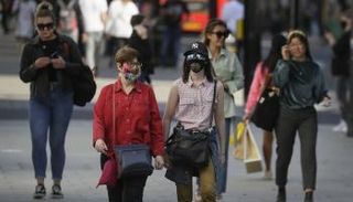 مارة يرتدون كمامات للوقاية من كورونا في بريطانيا