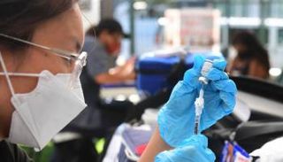 عاملة صحية تحمل جرعة من لقاح كورونا