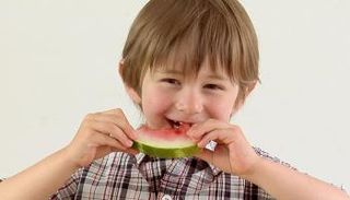 طفل يتناول قطعة بطيخ