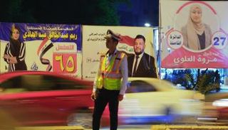 لافتات انتخابية يتقدمها شرطي مرور في العاصمة بغداد