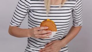 سيدة تمسك بمعدتها بعد تناول الطعام