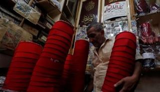 عبدالباسط يحمل مجموعة من الطرابيش التي صنعها بنفسه في مصر