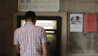 سوري أمام ماكينة صراف آلي تتبع المصرف الدولي للتجارة