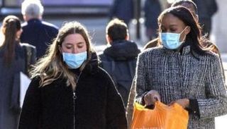 سيدتان تسيران في الشارع بالكمامة